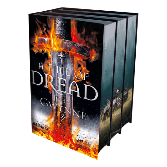 Three hardcover books with the front cover of "A Time of Dread" by John Gwynne prominently displayed, depicting a burning sword.