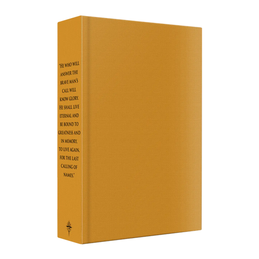 A textured, mustard-yellow hardcover book stands upright, featuring a motivational quote in black text on its spine.